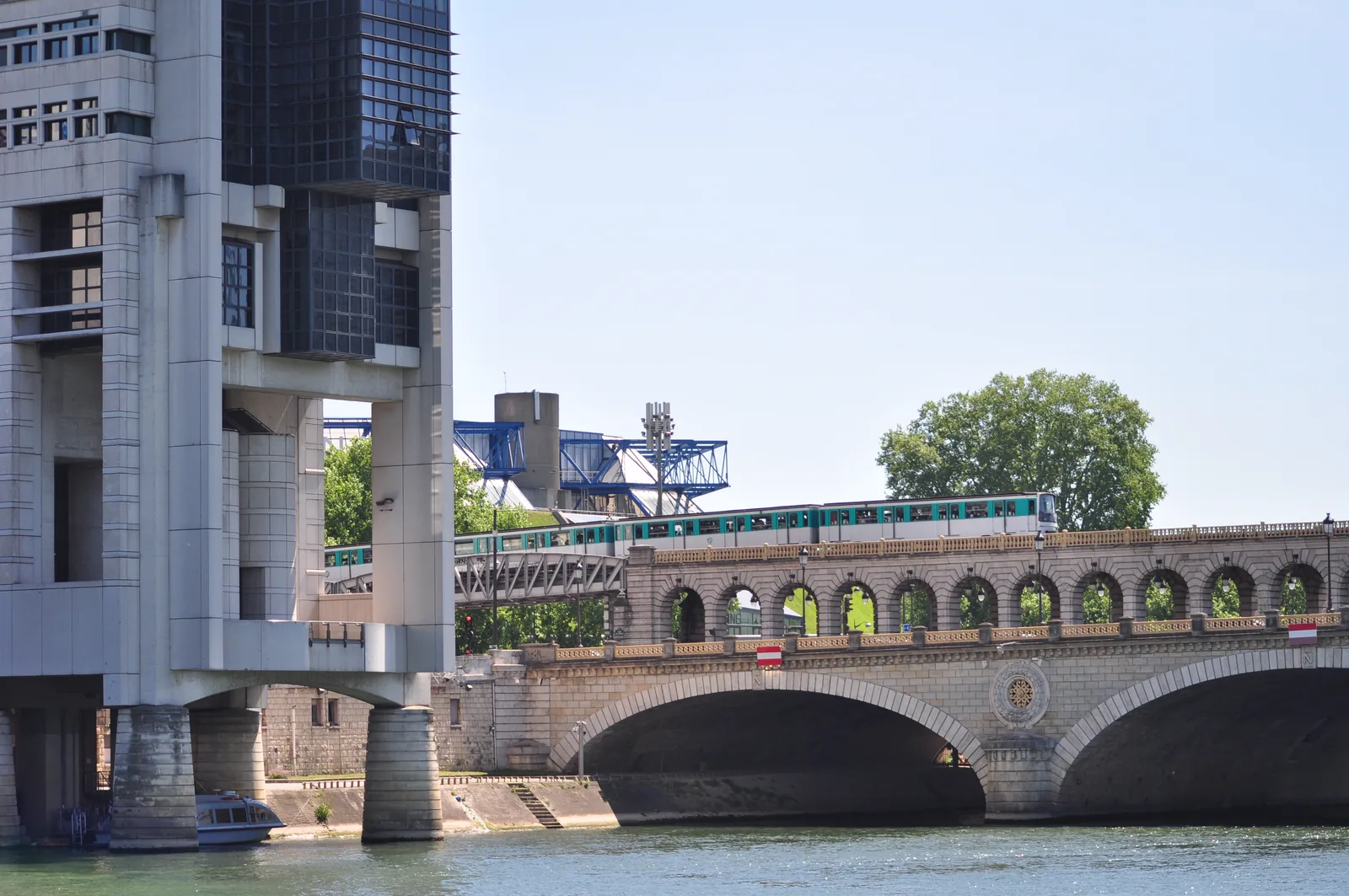 A metro train crossing the Pont de Bercy over the Seine in Paris, with the Colbert building of France's Ministry of Economy and Finance behind