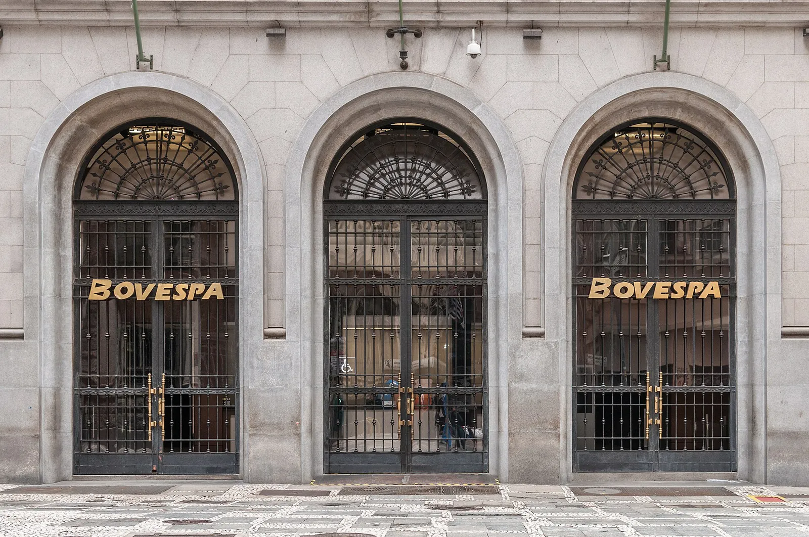 Вход в здание биржи с тремя арками и коваными решётками и надписью BOVESPA в центре Сан-Паулу