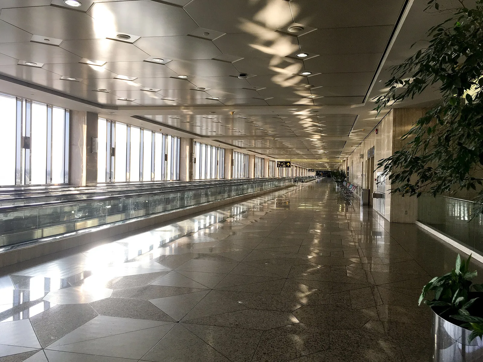 达曼法赫德国王国际机场空荡荡的长航站楼走廊,地面光亮,设有自动人行道