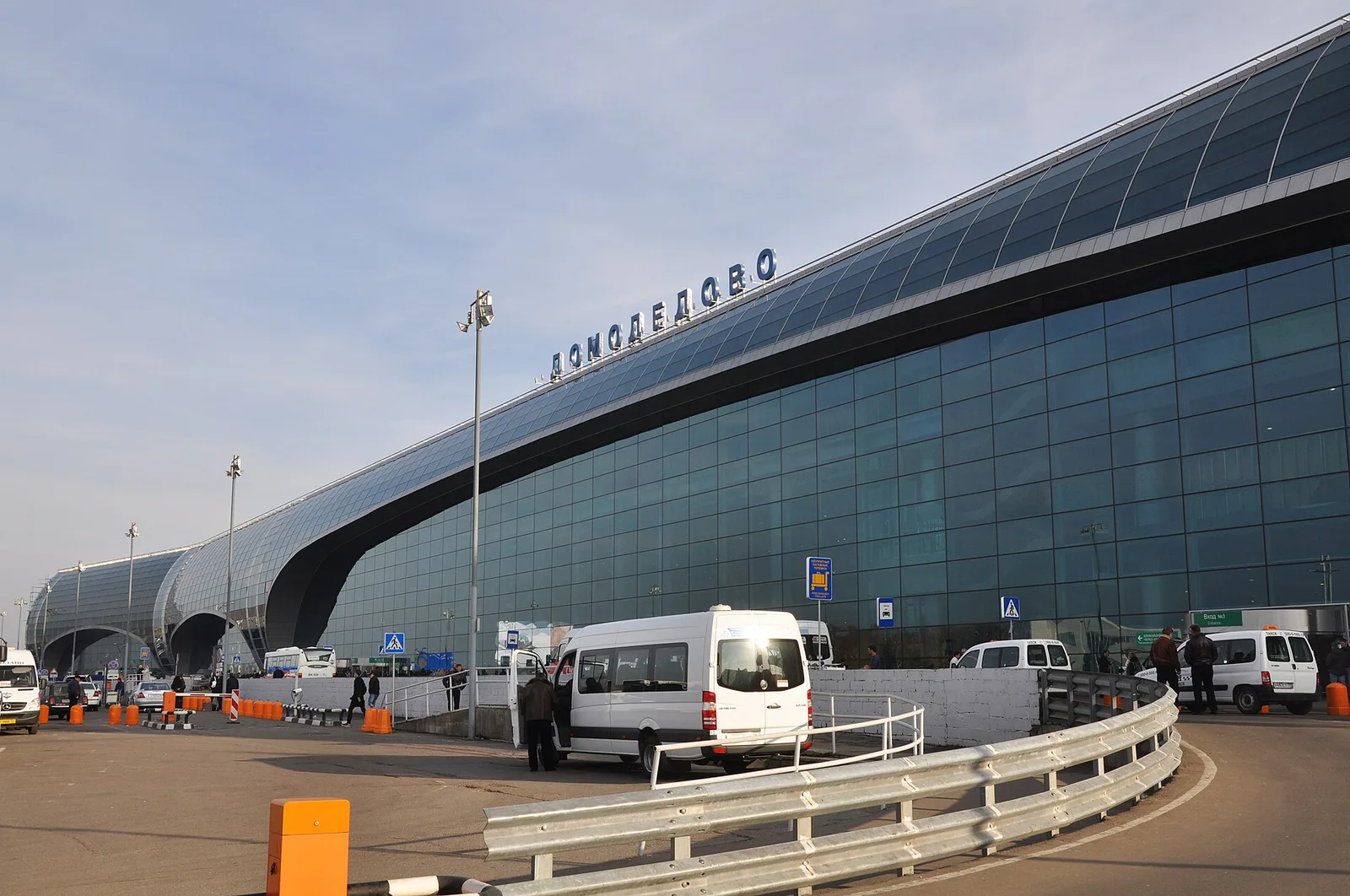 The curved glass terminal building of Moscow's Domodedovo Airport and the access road in front