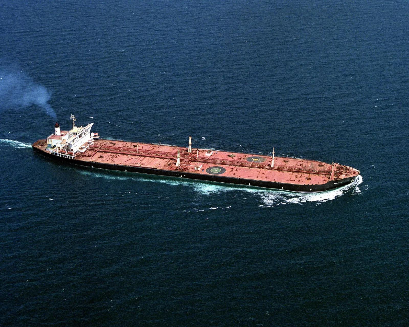 Aerial view of a long crude oil tanker with a red deck under way on deep blue sea