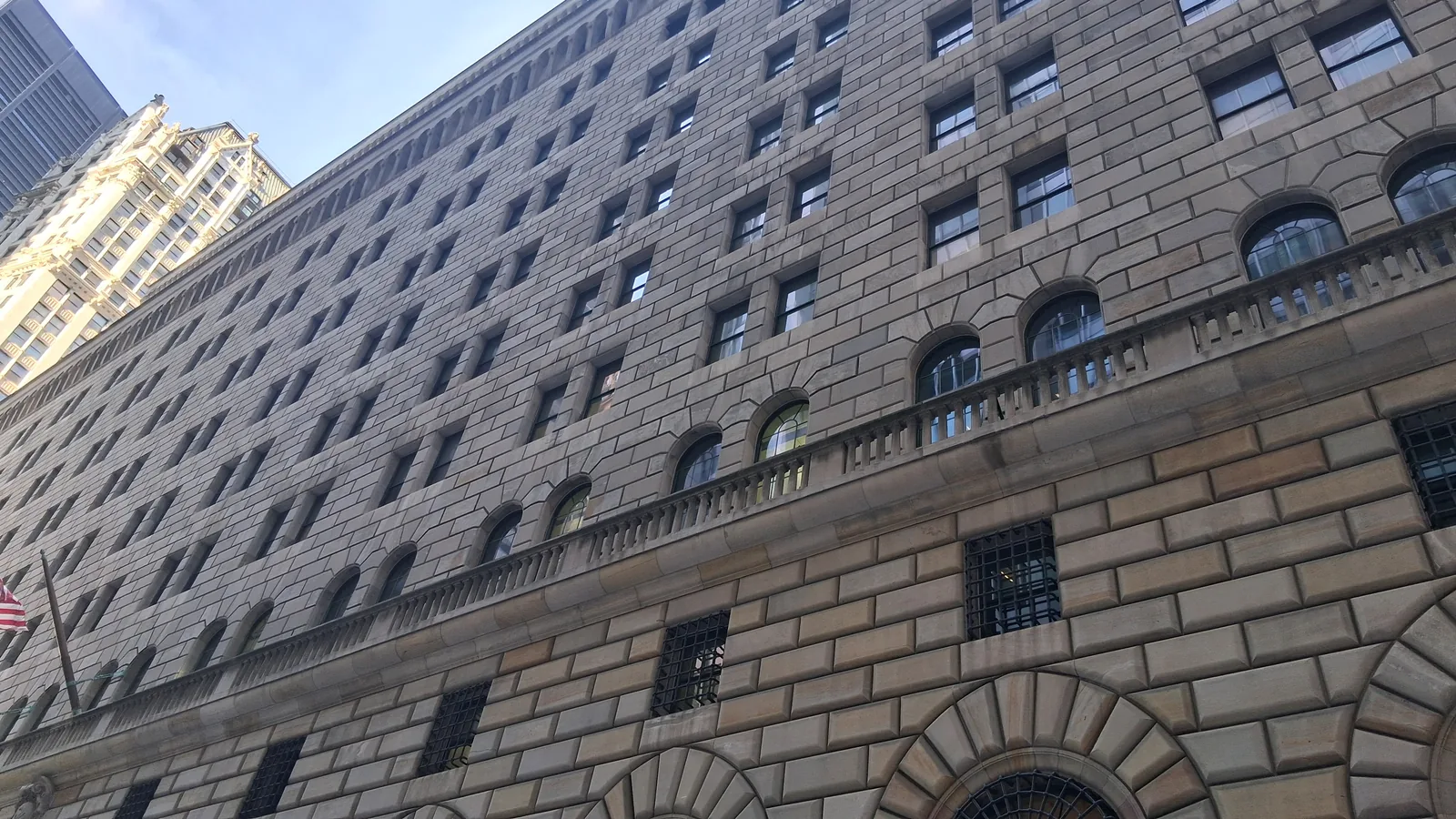 Manhattan'da kemerli pencereli, kesme taştan yüksek Federal Reserve Bank of New York binasının aşağıdan görünümü