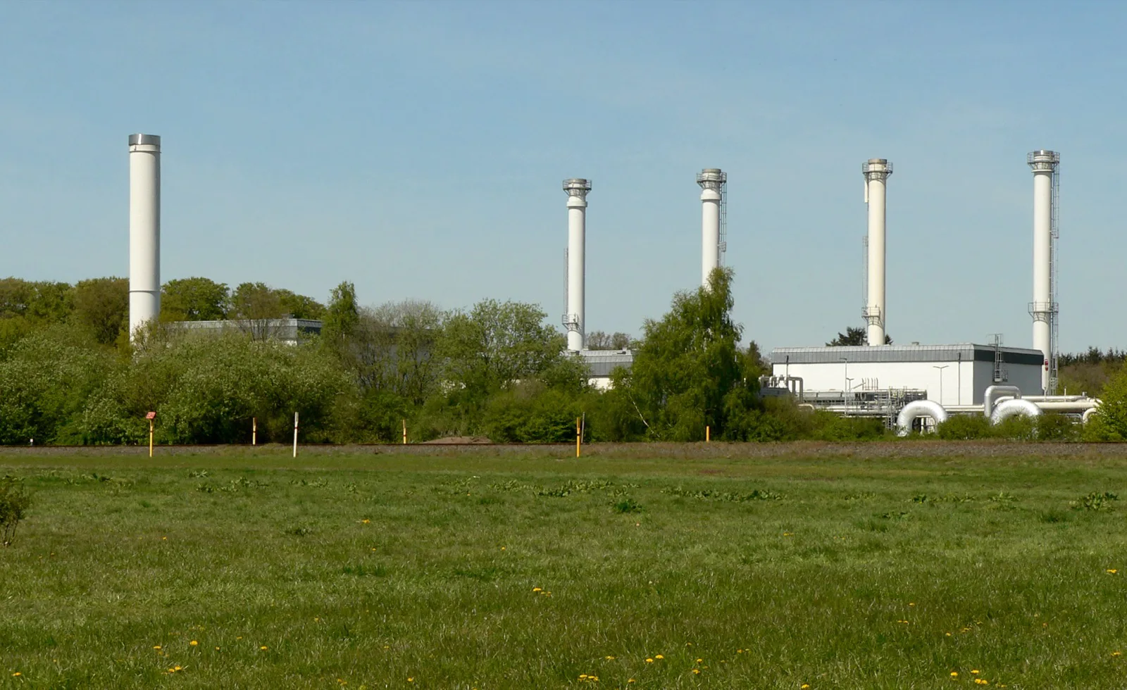 White stacks and above-ground compressor buildings of the Rehden underground gas storage facility in Lower Saxony, Germany