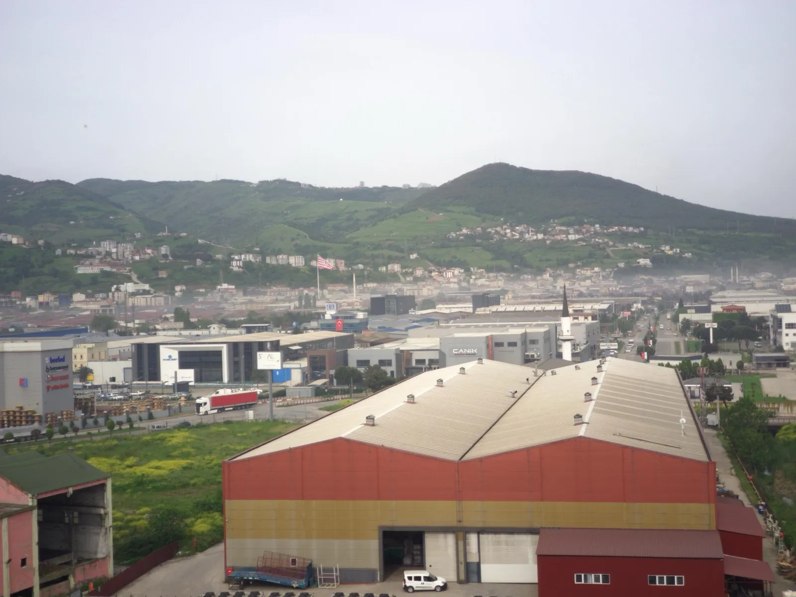 Factory buildings and warehouses in Samsun Organised Industrial Zone, with a road running towards green hills