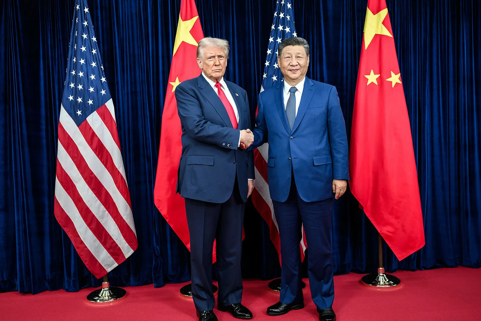 Donald Trump and Xi Jinping shaking hands in front of U.S. and Chinese flags