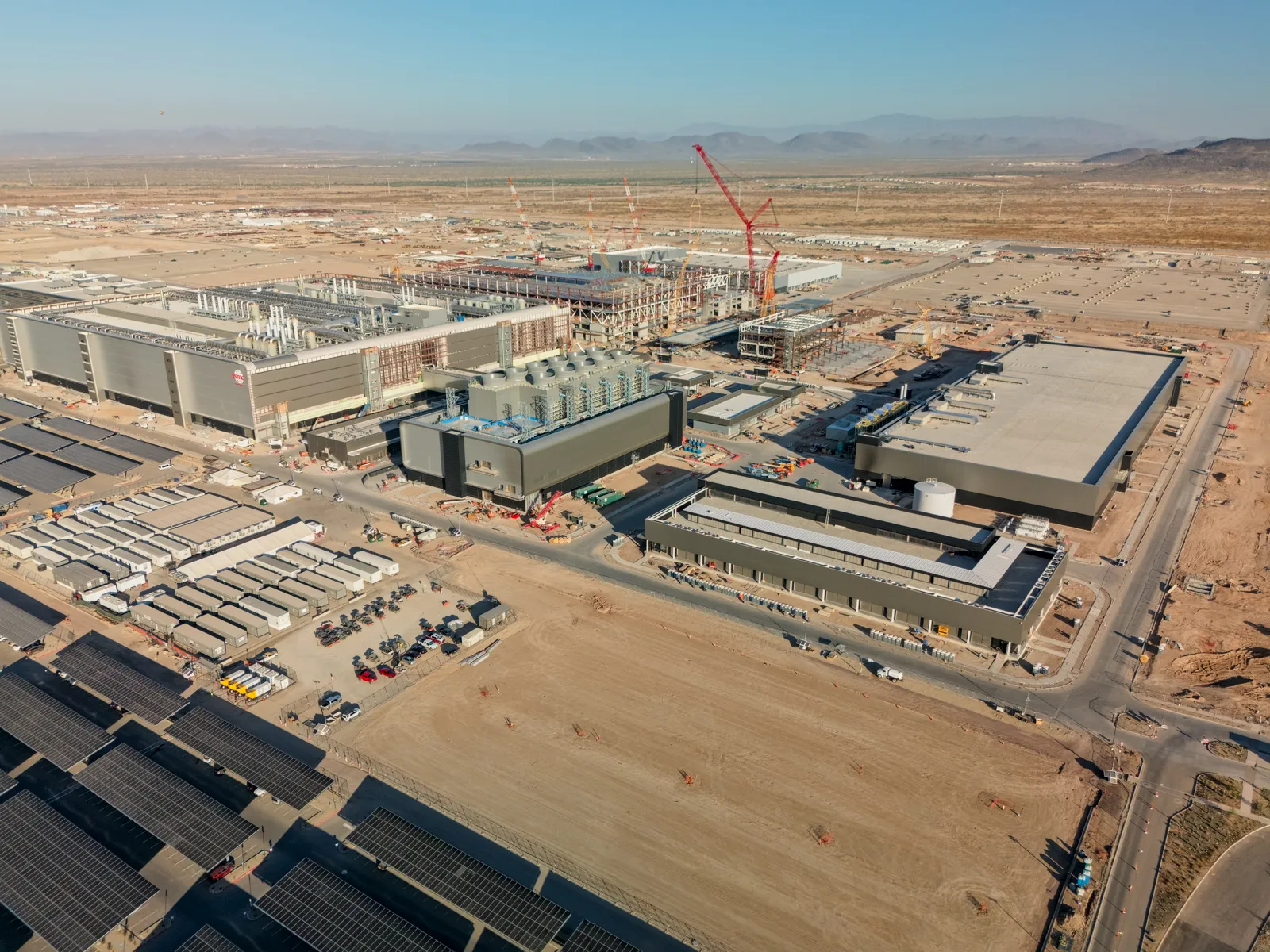 Вид с воздуха на строящийся кампус TSMC Fab 21 в пустыне Аризоны: корпуса фабрики, краны и парковка с солнечными навесами